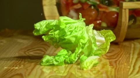 Dropping lettuce over  vegetarian salad by woman hand in home kitchen Stock Footage 231897142