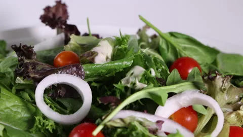 Dropping pouring caesar sauce sliced onion tomato mixed green salad leafs on whi Stock Footage 144310052