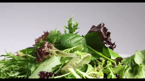 Dropping pouring caesar sauce sliced onion tomato mixed green salad leafs on whi Stock Footage 144310911