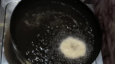 Dropping raw batter into hot oil to fry tootu vada close up Stock Footage 336061732