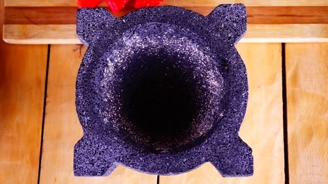 Dropping red hot chilli peppers in a morter Stock Footage 129401287