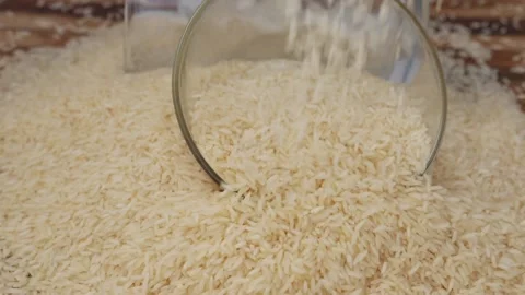 Dropping rice over a half bowl stuck in the heap of rice Video stock 147694468