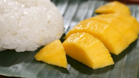 Dropping ripe mango slice on banana leaf with sticky rice Stock-Footage 182739209