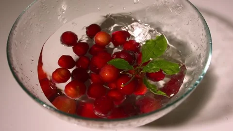 Dropping ripe red cherries fruit in a bowl of water Stock Footage 346720404