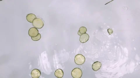 Dropping slices of cucumber into water Stock Footage 121220736
