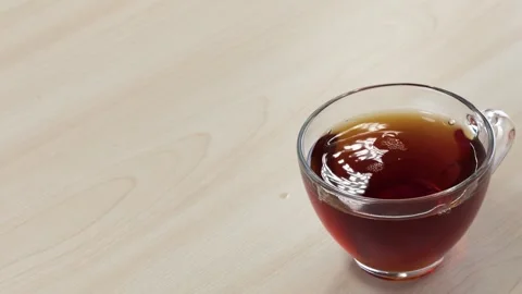 Dropping Sugar Cubes into a Glass Cup of Black Tea Stock Footage 345710372