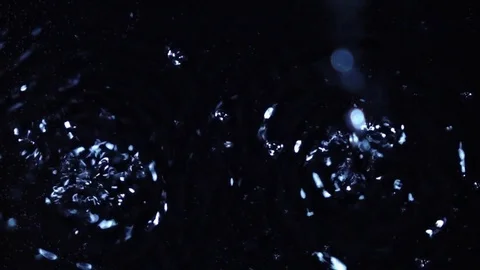 Drops are falling into dark water from blur to focus in extreme slow motion Stock Footage