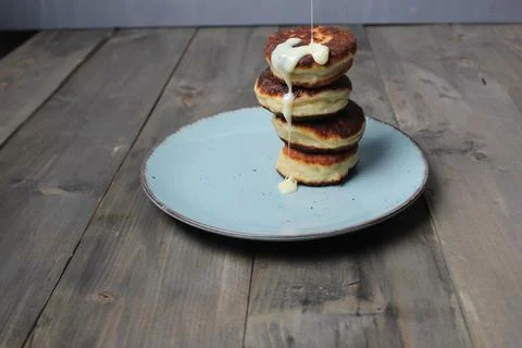Drops of condensed milk drip from cheesecakes on a plate. nasser background.  Stock Photos