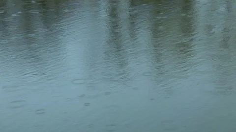 Drops of drizzly summer rain falling on the pond abstract pattern of splashes of Stock Footage 129975236