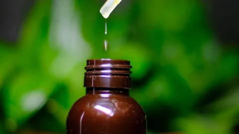 Drops of extract or plant or essential oil drip into a bottle Stock Footage 120573768