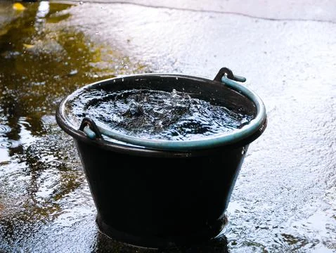 Drops fall into a dark container, demonstrating meteorological rainwater Fotos Stock