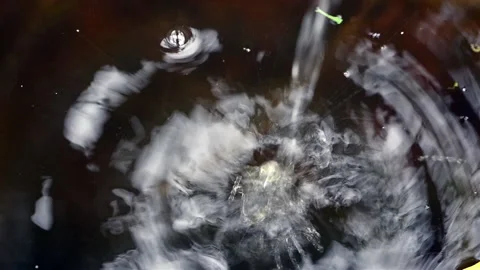 Drops fall into a puddle: slowly at first, then a lot and fast Stock-Footage 135511733