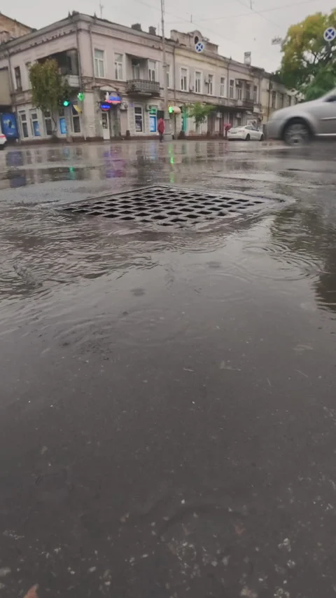 Drops fall into puddles and flows in drainage system, scene of city life during Vídeo Stock 331609200