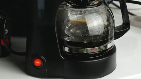 Drops fall into a transparent teapot.Black plastic case and red button. Stock Footage 143772423