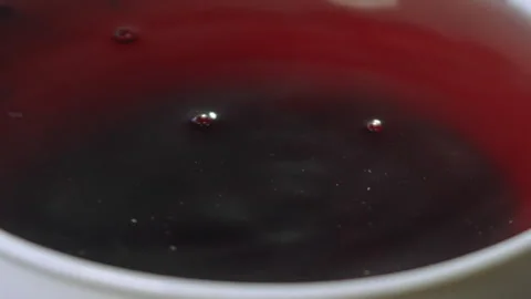 Drops falling into a red cup of tea Stock Footage 274697060