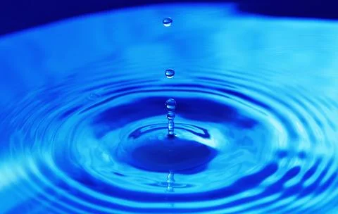 Drops falling in water and circles walking on water, with reflection. Blue .. Stock Photos