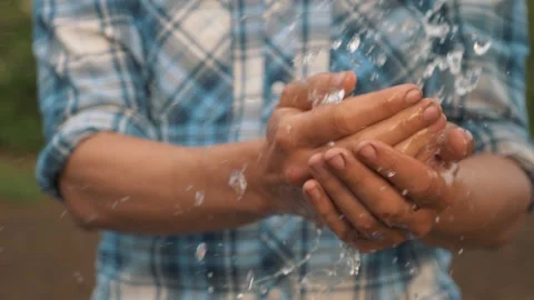 Drops of fresh water fall on the hands o... | Stock Video | Pond5