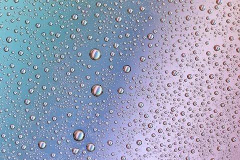 Drops on glass of different sizes and colors on a colored background, texture Stock Photos