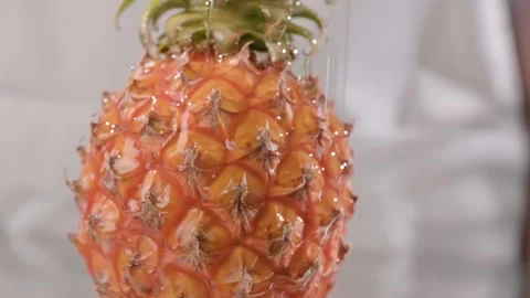 Drops of honey fall beautifully on pineapple, close-up. honey flows down on a Stock Footage 153580575