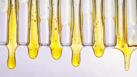 Drops of honey flow down glass tubes Stockbeeldmateriaal 258322387