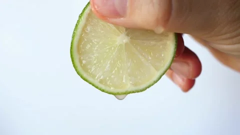 Drops of juice driping from slice of lime held in  fingers Stock-Footage 134287207