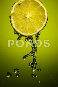 Drops of lime juice falling down. Colorful background Stock Photos