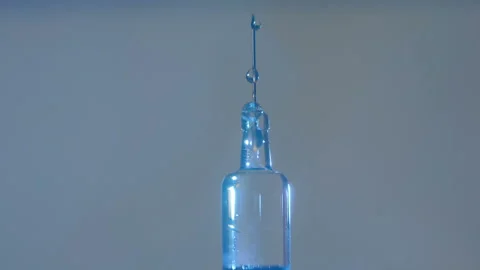Drops of medicine dripping down the needle of a glass modern syringe for vaccine Video stock 158083952
