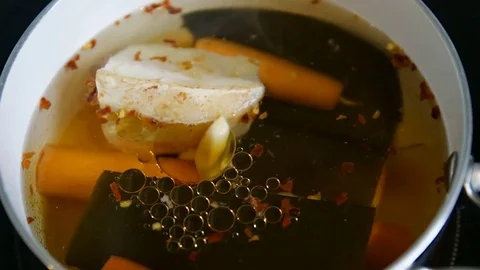 Drops of oily fat floating slowly in broth with seaweed and vegetables. Stock Footage 78734290