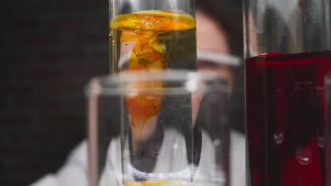 Drops of orange chemical reagent fall down into test tube Stock Footage 217953871
