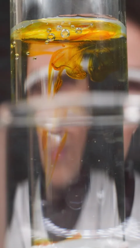 Drops of orange chemical reagent fall down into test tube Stock Footage 310865645