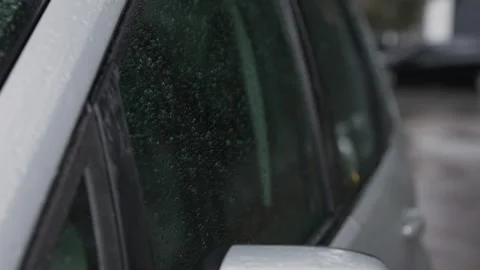 Drops of rain flow down the side window of a parked car Stock Footage 287312489