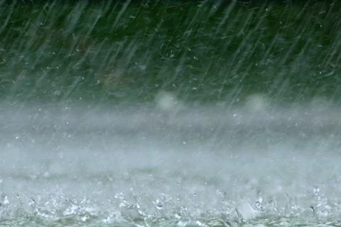 Drops of rain splash in the puddle. Stock Photos