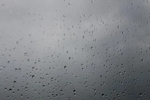 Drops of rain on the window with cloudy background. Stock Photos