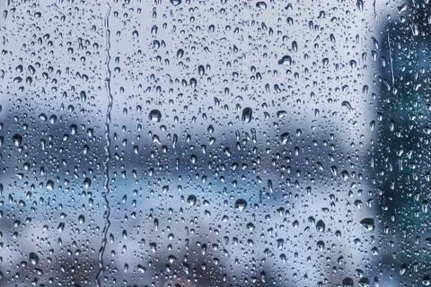 Drops of rain on window during the storm with blur background Stock Photos