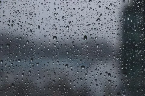 Drops of rain on window during the storm with blur background Stock Photos