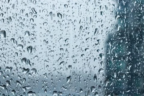 Drops of rain on window during the storm with blur background Stock Photos