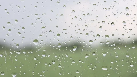 Drops of rain on a window glass overlooking a green field and blue sky Stock Footage 78090239