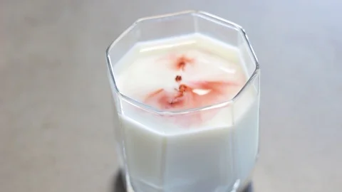 Drops of red liquid in a glass of milk. Red circles on a white surface. Stock Footage 112939482