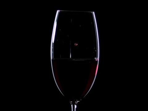 Drops of red wine drip in the glass filled with red wine. Stock Footage 72476917