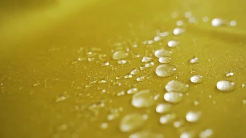 Drops roll down the yellow water-repellent fabric Stock Footage 183466543