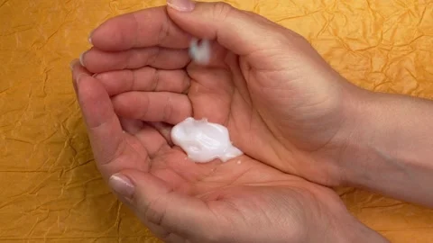 Drops of soothing moisturizing cream fall on open female palms yellow background Stock Footage 263744492