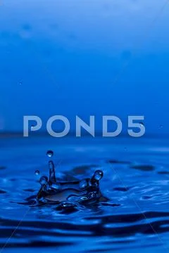 Drops, sprays, splashes of water on a colorful background Stock Photos