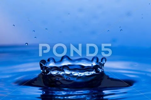 Drops, sprays, splashes of water on a colorful background Stock Photos