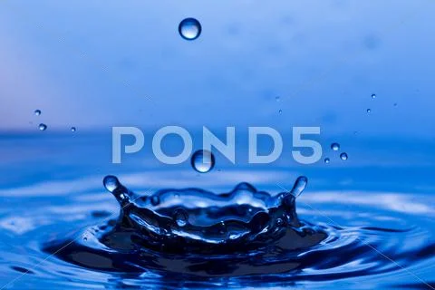 Drops, sprays, splashes of water on a colorful background Stock Photos