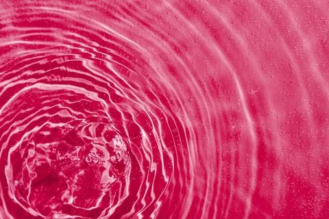 Drops on water with circles on a pink background Stock Photos