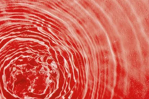 Drops on water with circles on a red background Stock Photos