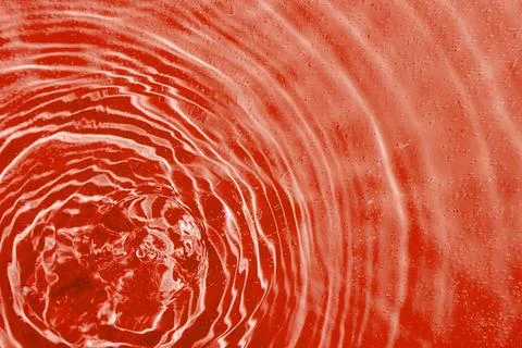 Drops on water with circles on a red background Stock Photos