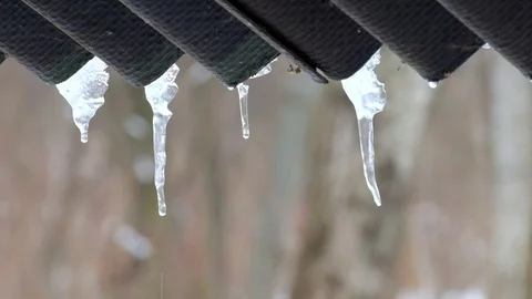 Drops of water drip from the icicles hanging under the roof Stock Footage 86208936