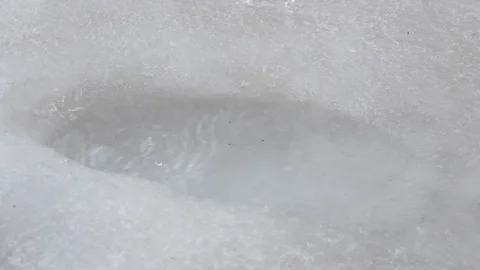 Drops of water drip into a puddle in ice and spray and waves in the spring. Stock Footage 125177061