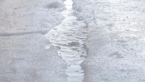 Drops of water drip into a puddle in ice and spray and waves in the spring. Stock Footage 125177182